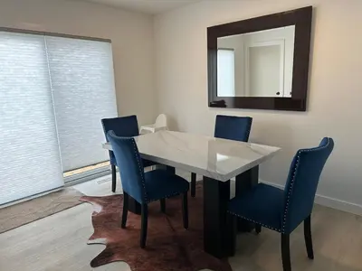 a dining room table with blue chairs and a mirror at Modern new townhouse in Red Deer