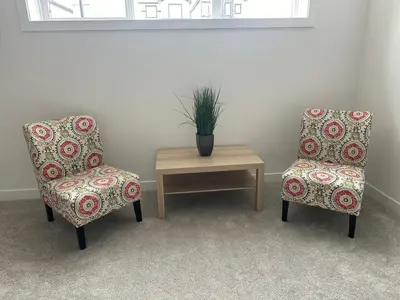 two chairs and a table with a potted plant on it at Modern new townhouse in Red Deer