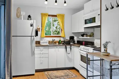 a kitchen with white cabinets and a white refrigerator at Little Bear Cabin at Raven's Moon in Ucluelet