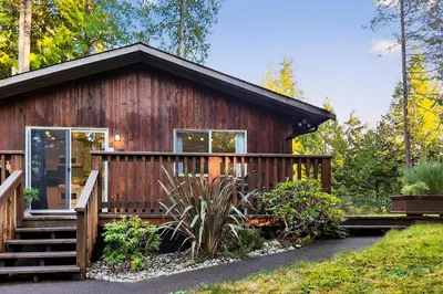 a cabin in the woods with a deck and stairs at Little Bear Cabin at Raven's Moon in Ucluelet