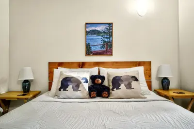 a teddy bear sitting on a bed with pillows at Little Bear Cabin at Raven's Moon in Ucluelet