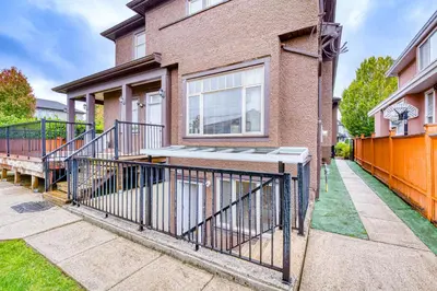 a brick house with an orange fence in front of it at Cozy two beds lower level suite in Vancouver West in Vancouver