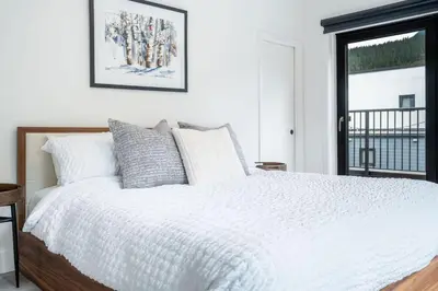 a bedroom with a white bed and a window at The Begbie Penthouse in Mackenzie Village in Revelstoke