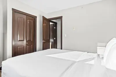 a bedroom with a white bed and a wooden door at Bears Den 2BR Getaway with Hot Tub, BBQ Near DT in Dead Man's Flats