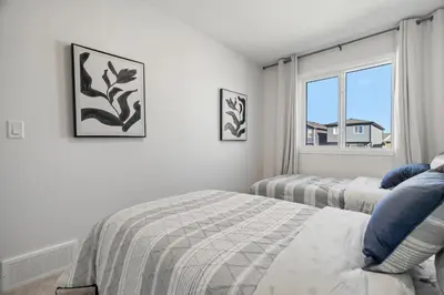 a white bedroom with two beds and a window at Brand New Cozy2BR House NW Calgary DT Banff Sleep4 in Calgary