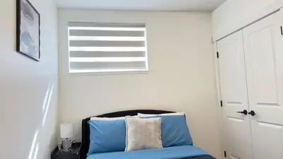a bedroom with a blue bed and a window at Northern Nook - 2BR Suite in Calgary