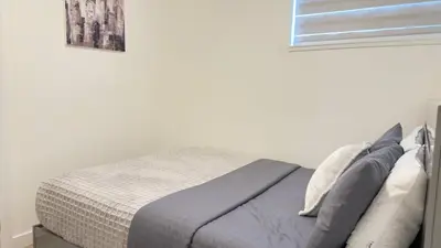 a bed in a white bedroom with a window at Northern Nook - 2BR Suite in Calgary