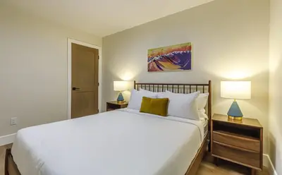 a bedroom with a large white bed with two lamps at Aurora Lite - Brand new suite with private entrance in Canmore