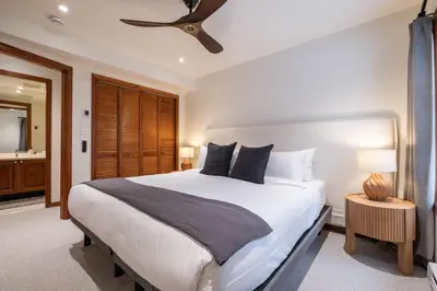 a bedroom with a large white bed and a bathroom at Blackcomb Greens 33 by Outpost Whistler in Whistler