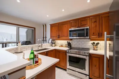 a kitchen with wooden cabinets and stainless steel appliances at Blackcomb Greens 33 by Outpost Whistler in Whistler
