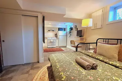 a bedroom with a bed and a room with a kitchen at Cozy Boho Studio Suite in Calgary