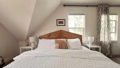 a bedroom with a large white bed with two windows at Charming Inner City Home in Calgary