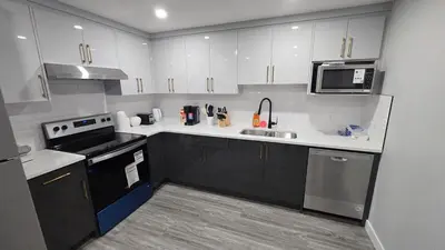 a kitchen with white cabinets and a sink and a microwave at Royaldee Cozy Home in Calgary