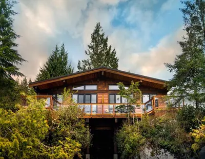 a large wooden house with a wrap around deck at Wild Renfrew Seaside Cottages in Port Renfrew