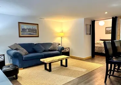 a living room with a blue couch and a bed at Suite on the Bay in Marsh Lake