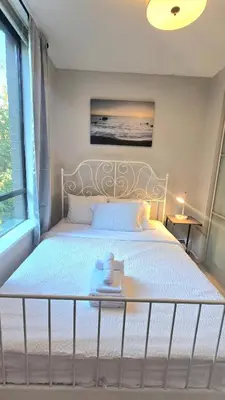 a bed with a white bed frame and a window at Bright 2BR Close to Seabus, and Lower Lonsdale in North Vancouver