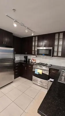 a kitchen with stainless steel appliances and wooden cabinets at Bright 2BR Close to Seabus, and Lower Lonsdale in North Vancouver