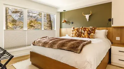 a bedroom with a large bed with a fur blanket on it at Ravens Nest - Private Hot Tub in Canmore
