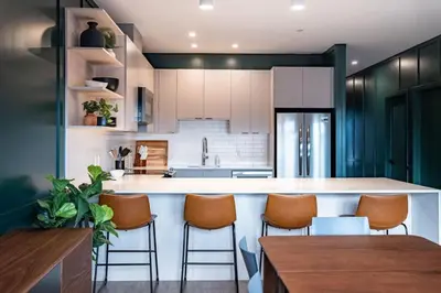 a kitchen with white cabinets and a bar with stools at Revelstoke Mountain Penthouse in Revelstoke