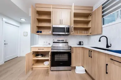 a kitchen with wooden cabinets and a stove top oven at Newly built 2 bedroom suite with kitchen & laundry in Calgary