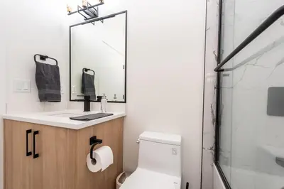 a bathroom with a toilet and a sink and a mirror at Newly built 2 bedroom suite with kitchen & laundry in Calgary