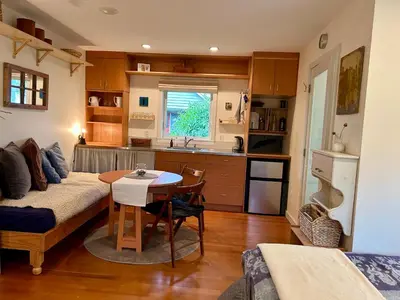 a living room with a table and a kitchen at Studio Cedar Guest Cottage in Duncan