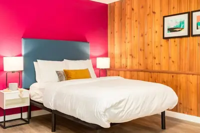a bedroom with a king sized bed with pink walls at Gateway Suites Perfect rest on your way to Banff in Canmore