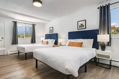 two beds in a room with two windows at Gateway Suites Lovely views near Banff in Canmore