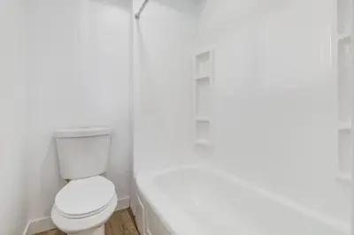 a white bathroom with a toilet and a bath tub at Gateway Suites Lovely views near Banff in Canmore