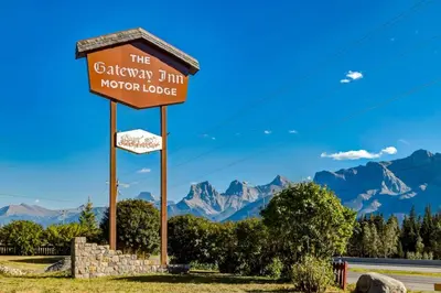 a sign for the gibraltar inn motor lodge with mountains in the background at Gateway Suites Cozy stay to explore Banff and Canmore in Canmore