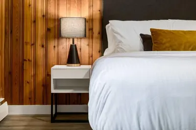 a bedroom with a white bed and a lamp on a night stand at Gateway Suites Cozy stay to explore Banff and Canmore in Canmore