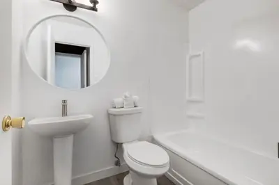 a white bathroom with a sink and a toilet and a mirror at Gateway Suites Sweet Getaway near Canmore and Banff in Canmore