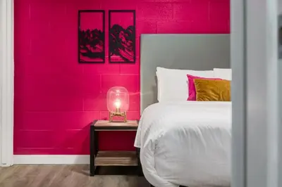 a pink bedroom with a bed and a table with a lamp at Gateway Suites Sweet Getaway near Canmore and Banff in Canmore