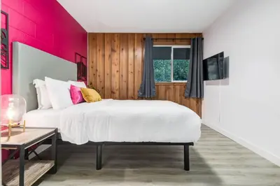 a bedroom with a white bed and a pink wall at Gateway Suites Sweet Getaway near Canmore and Banff in Canmore