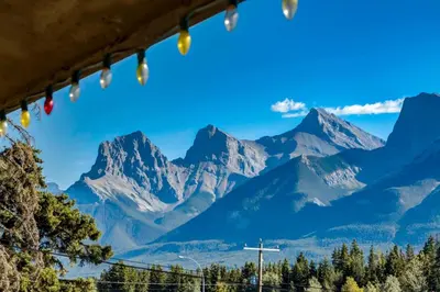 a view of mountains through a window with christmas lights at Gateway Suites Near Canmore and Banff in Canmore