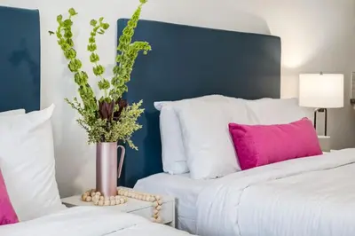 two beds with white and pink pillows and a vase with flowers at Gateway Suites Cozy Getaway Near Banff and Canmore in Canmore
