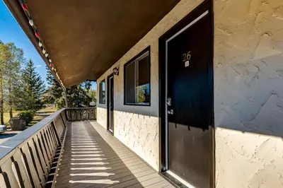 a porch of a house with a black door at Gateway Suites Cozy Getaway Near Banff and Canmore in Canmore