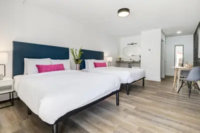 two beds in a large room with white and pink pillows at Gateway Suites Cozy Getaway Near Banff and Canmore in Canmore