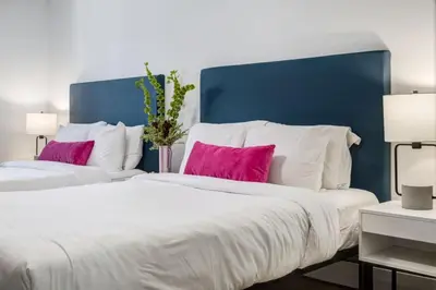 two beds with pink and white pillows in a bedroom at Gateway Suites Cozy Getaway Near Banff and Canmore in Canmore