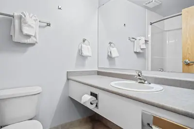 a bathroom with a sink and a toilet and a mirror at Stylish 1BR Haven in CanmoreDT near Banff Sleeps 4 in Canmore