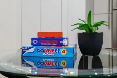 a stack of games on a glass table with a potted plant at Modern 2BR Private Suite Near Calgary Airport in Calgary