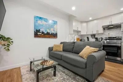 a living room with a gray couch and a kitchen at Modern 2BR Private Suite Near Calgary Airport in Calgary