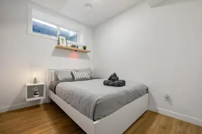 a white bedroom with a bed with a teddy bear on it at Modern 2BR Private Suite Near Calgary Airport in Calgary