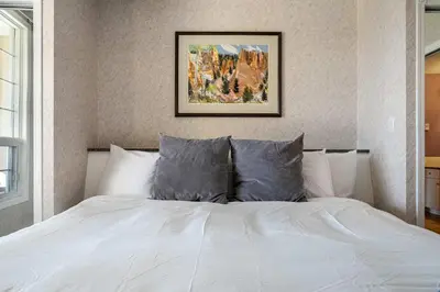 a bedroom with a white bed with a picture on the wall at The Pinnacle in Fairmont 1BR Condo Near Hot Springs in Fairmont Hot Springs