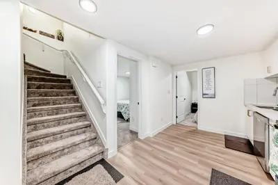 a staircase in a living room with white walls and wood floors at KimzNest in Edmonton