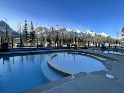 a large pool of water with mountains in the background at Black Bears Den, Heated Pool, Hot Tub, Brand NEW! in Canmore