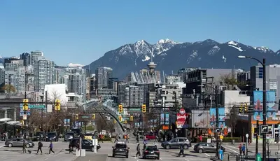 a busy city with cars and people crossing a street at Modern Private Suite with Parking - Cambie Village VGH in Vancouver