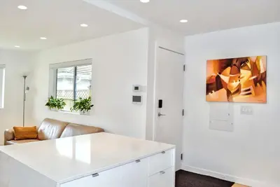 a white kitchen with a white counter and a couch at Modern Private Suite with Parking - Cambie Village VGH in Vancouver