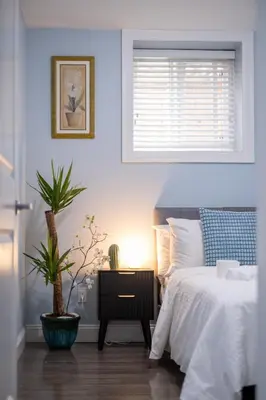 a bedroom with a bed and a night stand with a plant at 2 bedroom suite Walk to SkyTrain, Grocery, Macdonald & more in Vancouver