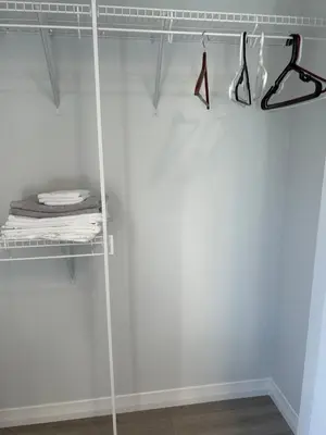 a walk in closet with a glass door and shelves at Sunny Queen-size Bedroom with Private Bath in Brand New House in Calgary